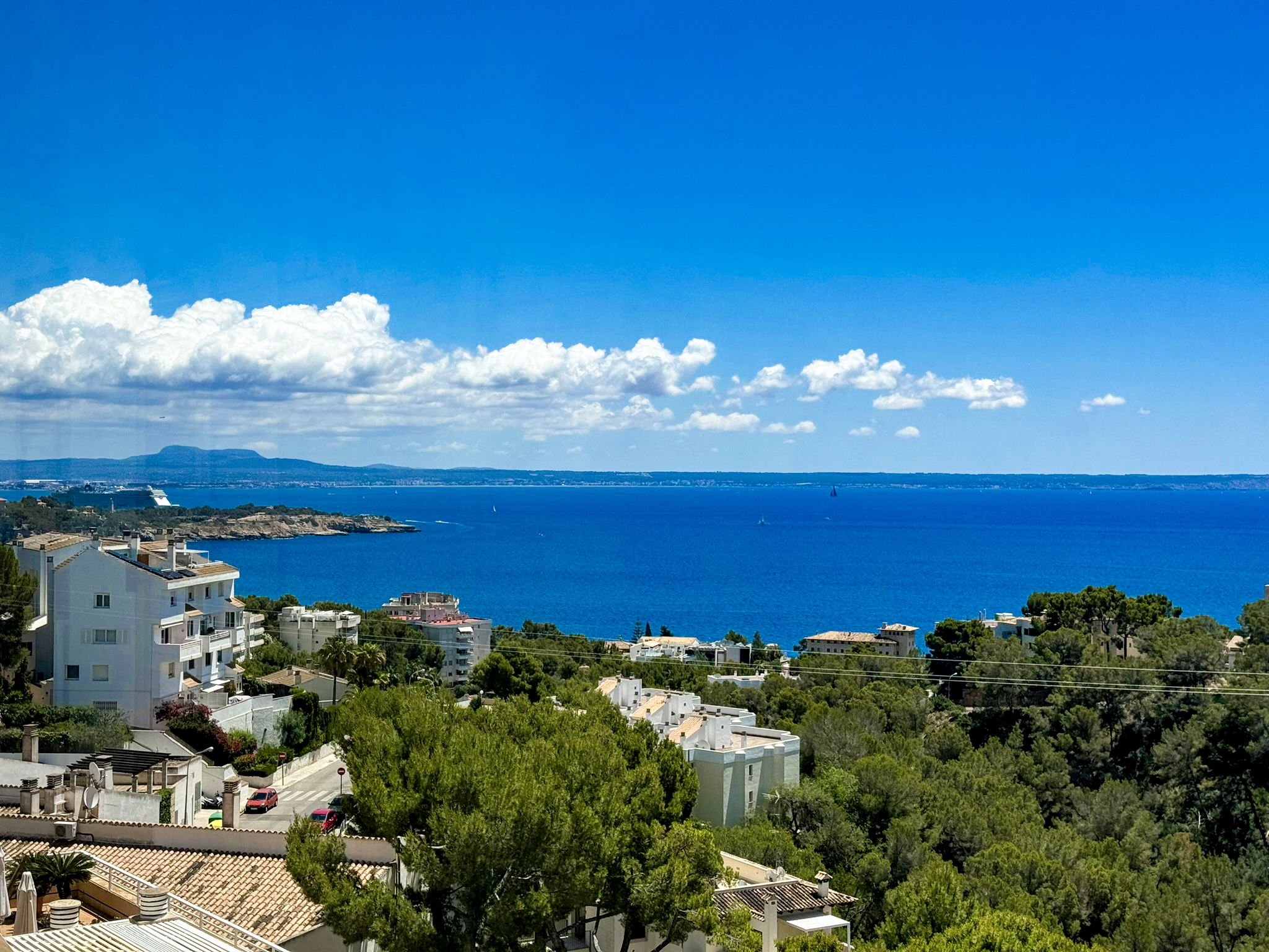 An image of a luxury apartment with a stunning sea view. The apartment features sleek, modern design with floor-to-ceiling glass windows that open to a spacious balcony. The balcony is furnished with elegant outdoor seating, perfect for enjoying the panoramic ocean vista. The shimmering blue sea stretches to the horizon, creating a serene and opulent atmosphere.